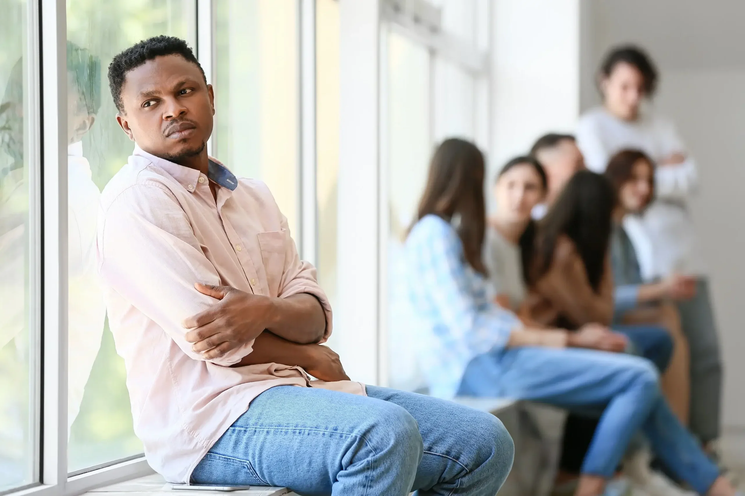 A black man sitting away from coworkers as an outcast.